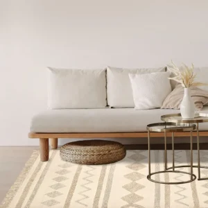 Tappeto berbero Naturale in cotone con geometrie marocchine in rilievo, colori avorio e sabbia, su pavimento chiaro con divano e tavolino dorato