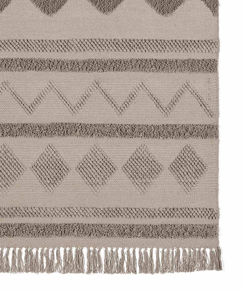 Tappeto berbero Taupe in cotone con geometrie marocchine in rilievo, colori avorio e sabbia, su pavimento chiaro con divano e tavolino dorato