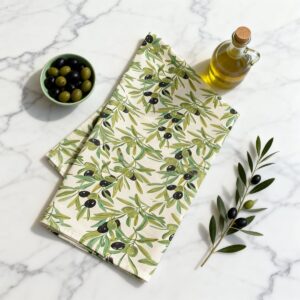 Tovaglia fantasia ulivo piegata su piano in marmo bianco con ciotola di olive e olio