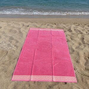 Telo mare rosa in spugna 100% cotone con bordo greca beige steso sulla sabbia vista dall'alto