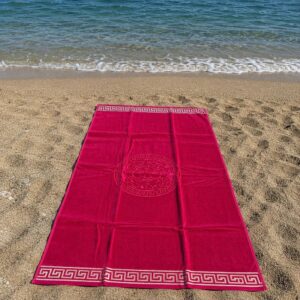Telo mare rosso corallo in spugna 100% cotone con bordo greca beige steso sulla sabbia vista dall'alto