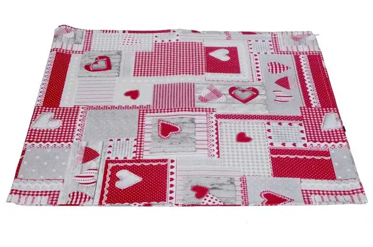 Dettaglio della tovaglia patchwork con cuori rossi e bianchi, quadretti, righe e riquadri con effetto legno grigio.