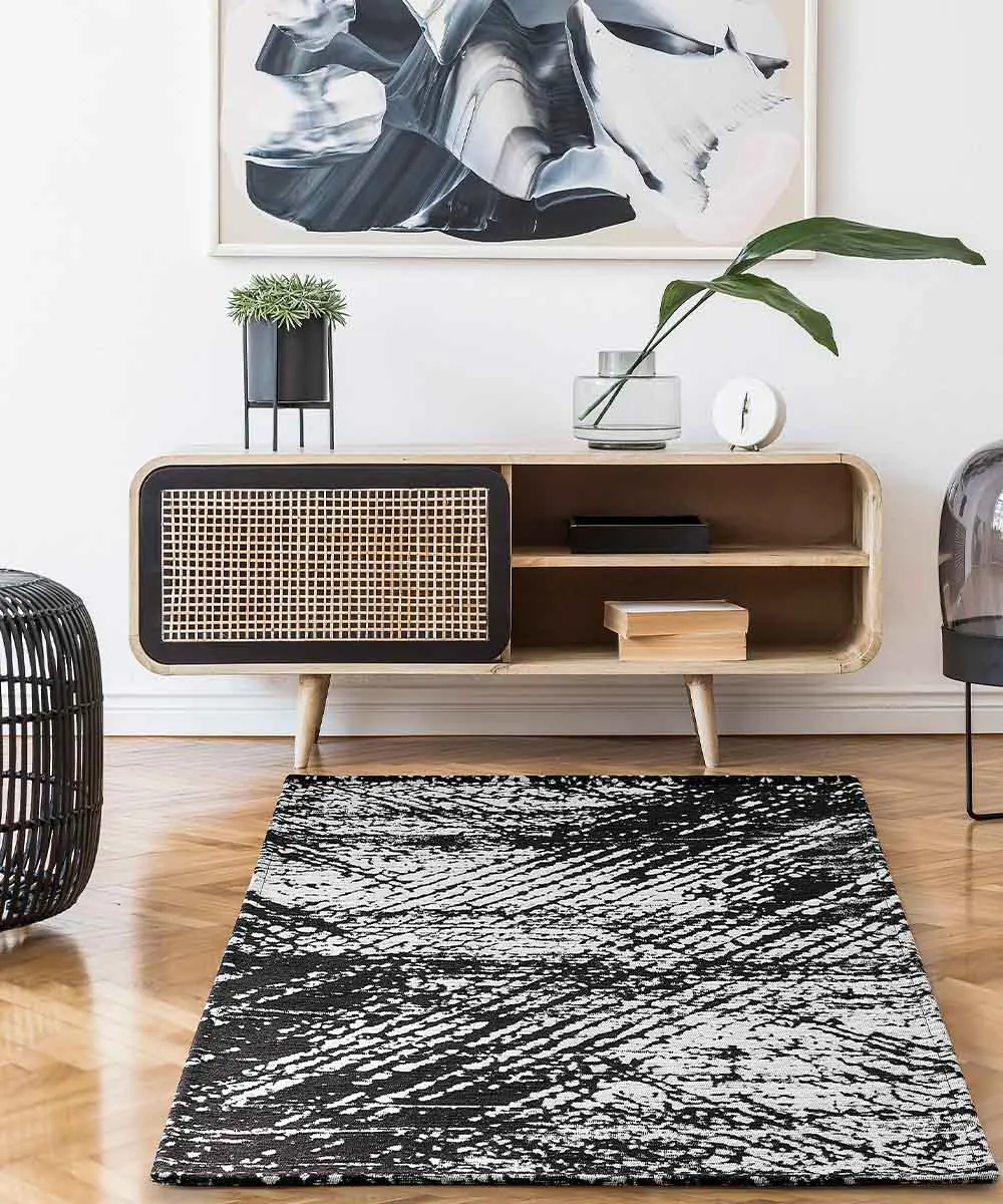 Tappeto moderno Essenza Nero antiscivolo in un soggiorno scandinavo con mobile in rattan e parquet