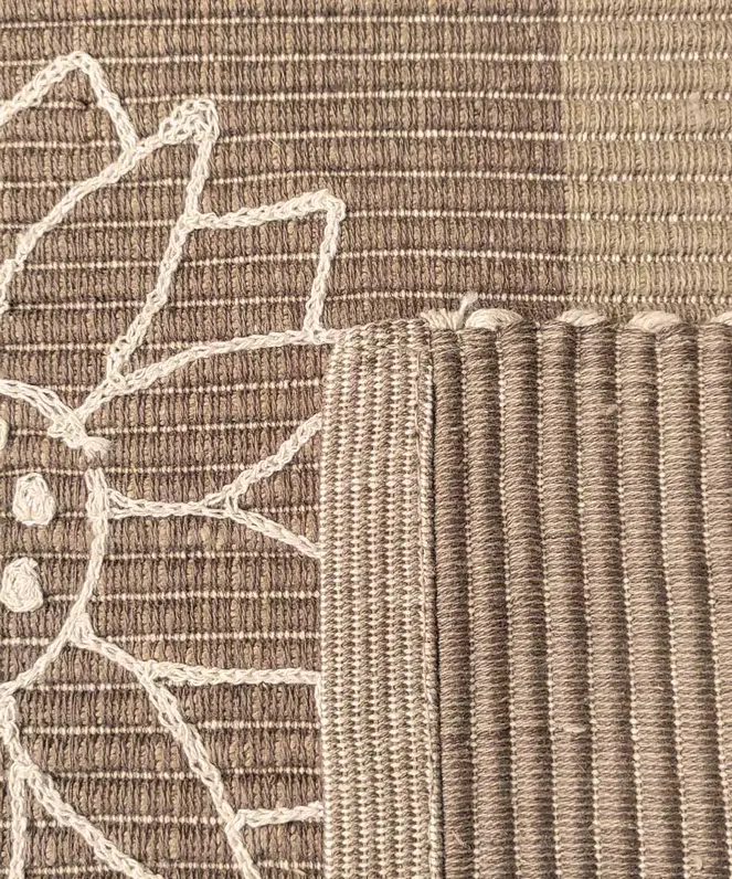 Dettaglio del ricamo a rilievo a punto catenella e della trama in cotone del tappeto Summer Beige